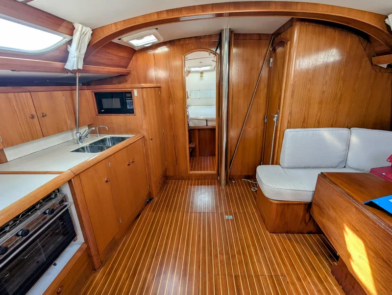 Slide: The Image of Interior of 1996 Jeanneau 45.1 sailboat with wood finish, kitchen, and seating area. - 23