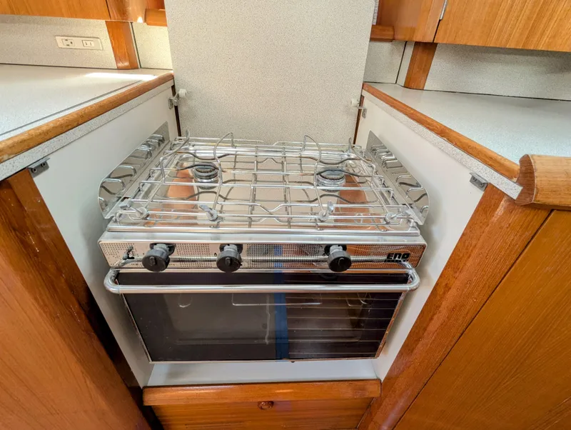 Slide: The Image of Gas stove and oven in 1996 Jeanneau 45.1 yacht kitchen, featuring wooden cabinetry. - 25