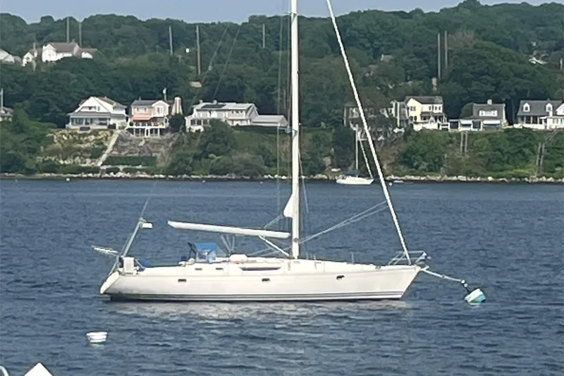 Slide: The Image of Sailboat Jeanneau 45.1 (1996) anchored on calm water with coastal houses in the background. - 47