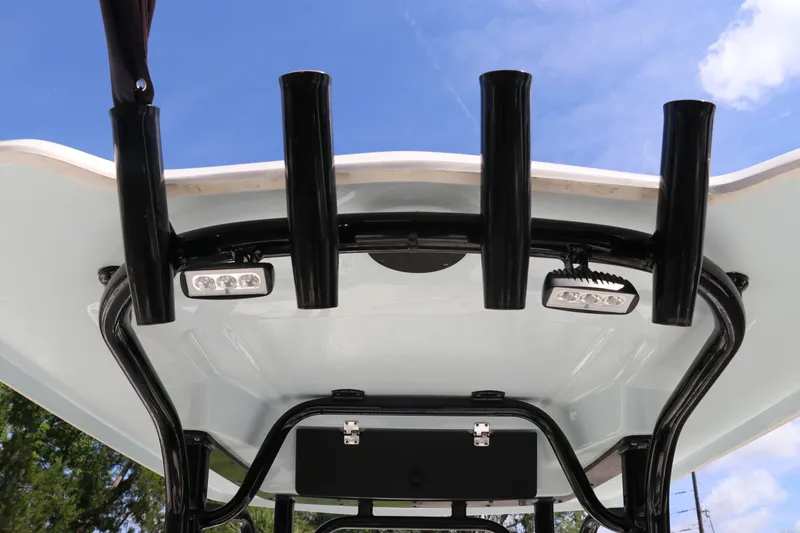 Slide: The Image of 2024 Robalo R230 Center Console T-top with rod holders and LED lights against blue sky. - 16