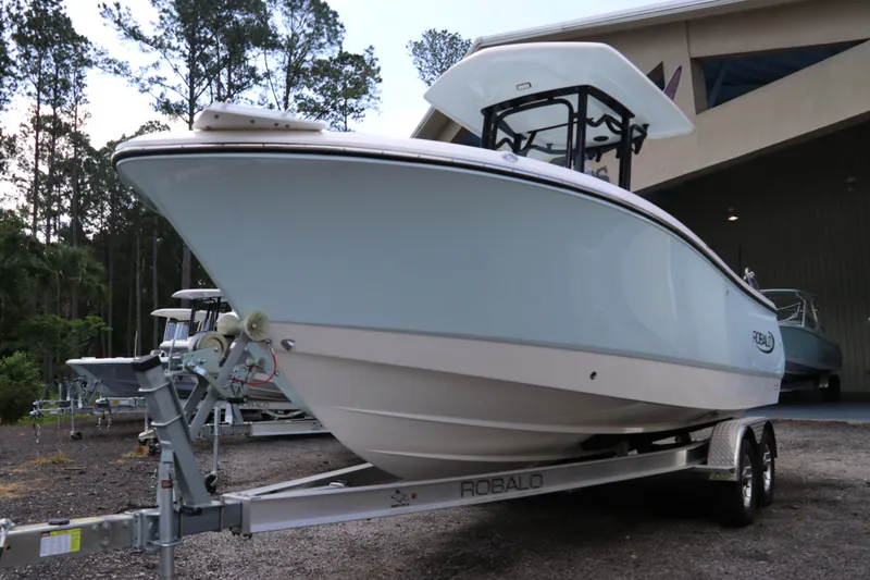 Slide: The Image of 2024 Robalo R230 Center Console boat on trailer, parked outdoors. - 2