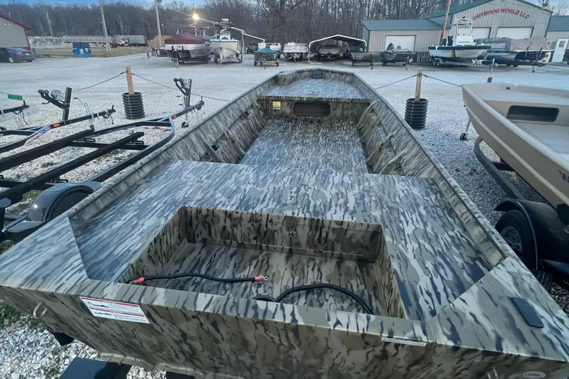 Slide: The Image of 2025 SeaArk 1648 MV Special boat with camouflage design in a boatyard setting. - 2