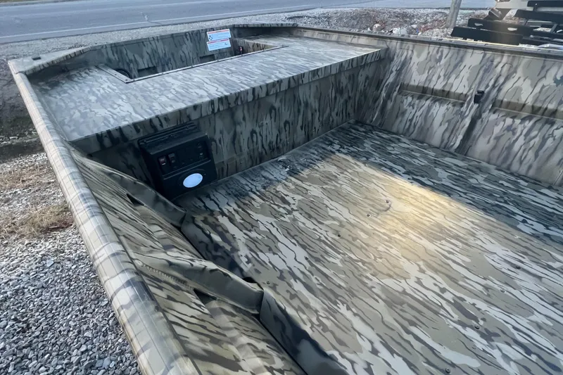 Slide: The Image of 2025 SeaArk 1648 MV Special boat with camouflage interior, parked on gravel. - 6