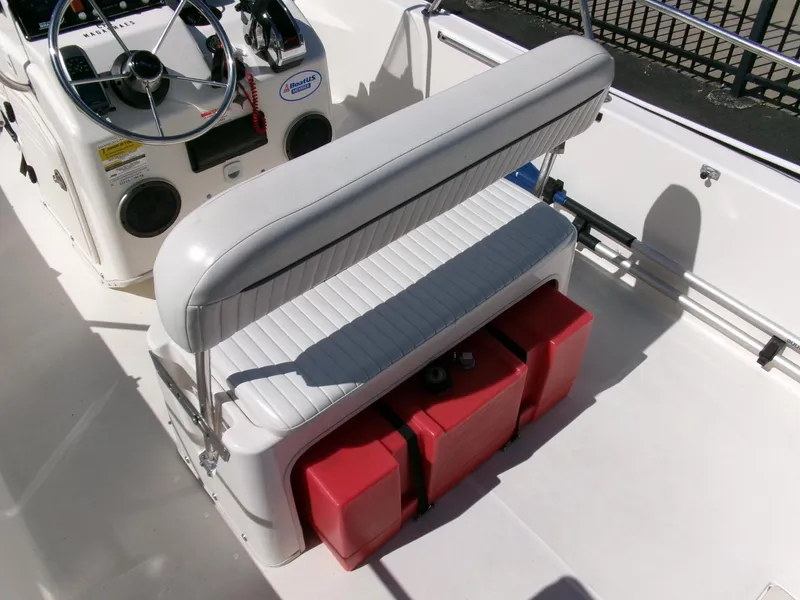 Slide: The Image of 2003 Boston Whaler 170 Montauk boat interior with steering console and red storage containers. - 15