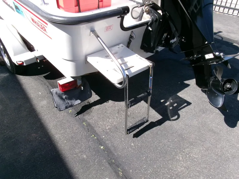 Slide: The Image of 2003 Boston Whaler 170 Montauk boat with ladder and motor, parked on pavement. - 19