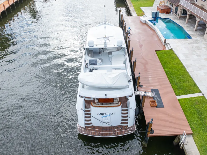 Slide: The Image of 2005 Hatteras 80 Motor Yacht docked beside a luxurious waterfront property with a pool. - 13
