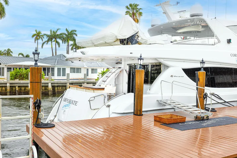 Slide: The Image of 2005 Hatteras 80 Motor Yacht docked by waterfront homes, surrounded by palm trees. - 14