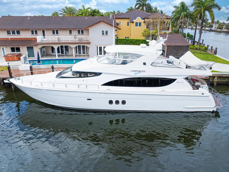 Slide: The Image of 2005 Hatteras 80 Motor Yacht docked near waterfront homes, surrounded by palm trees. - 2