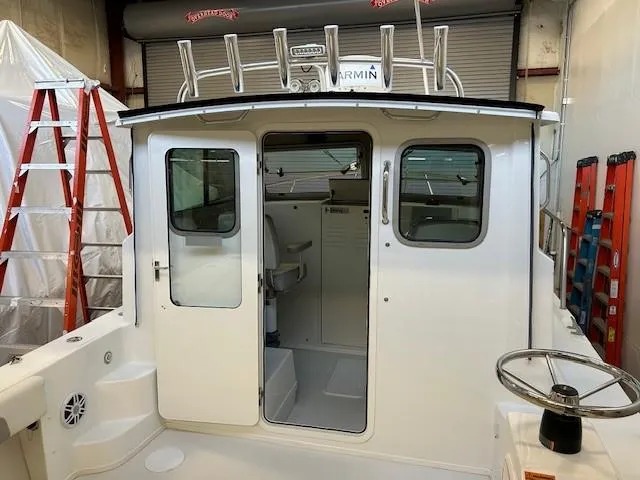 Slide: The Image of 2022 Parker 2520 XLD Sport Cabin boat interior with steering wheel and cabin door. - 6