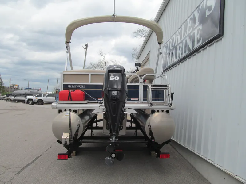 Slide: The Image of 2023 Sun Tracker Bass Buggy 16 XL Select pontoon boat with outboard motor, parked at a marina. - 4