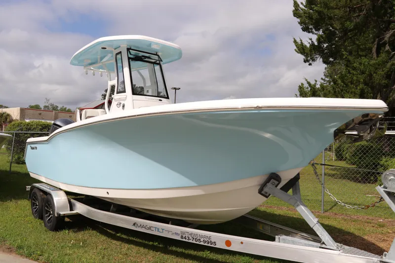 Slide: The Image of 2024 Tidewater 232 CC Adventure boat on trailer, light blue hull, parked on grass. - 0