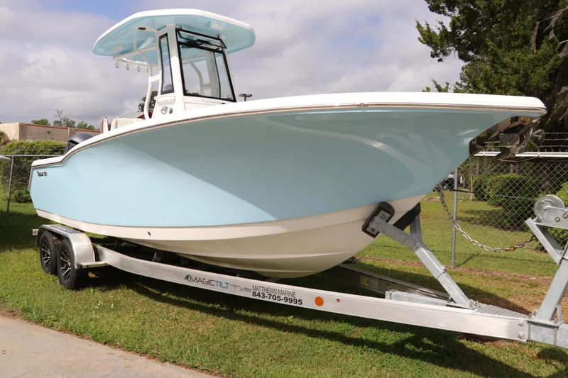 Slide: The Image of 2024 Tidewater 232 CC Adventure boat on trailer, light blue hull, parked on grass. - 1