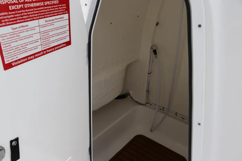 Slide: The Image of 2024 Tidewater 232 CC Adventure boat interior with storage compartment and hose. - 13