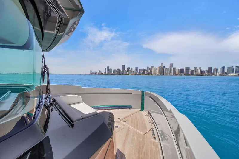 Slide: The Image of 2021 Explorer 62 yacht cruising with city skyline in the background, under a clear blue sky. - 44