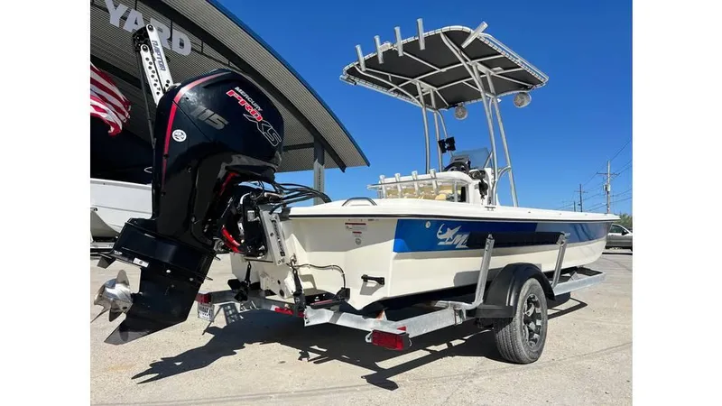 Slide: The Image of 2018 Mako Pro Skiff 19 CC boat on trailer with outboard motor, parked outdoors. - 10