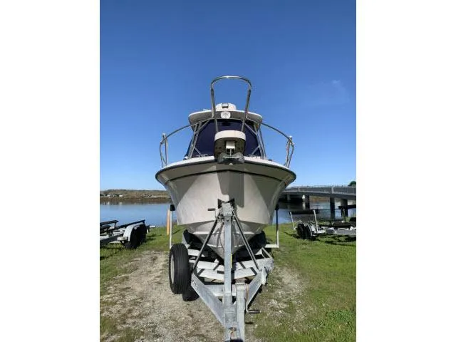 Slide: The Image of 2005 Grady-White 282 Sailfish boat on trailer, parked near a lake under clear blue sky. - 1