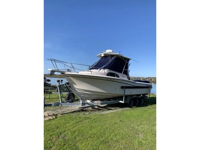 Slide: The Image of 2005 Grady-White 282 Sailfish boat on trailer, parked on grass under clear blue sky. - 24