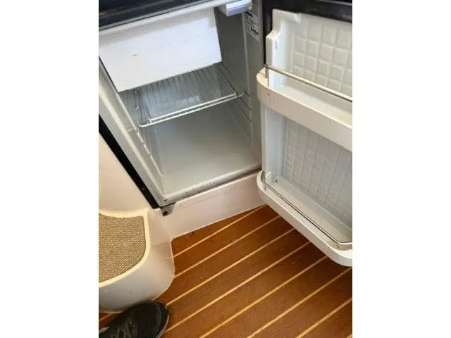 Slide: The Image of Open fridge inside 2005 Grady-White 282 Sailfish boat, showing interior and wooden floor. - 43
