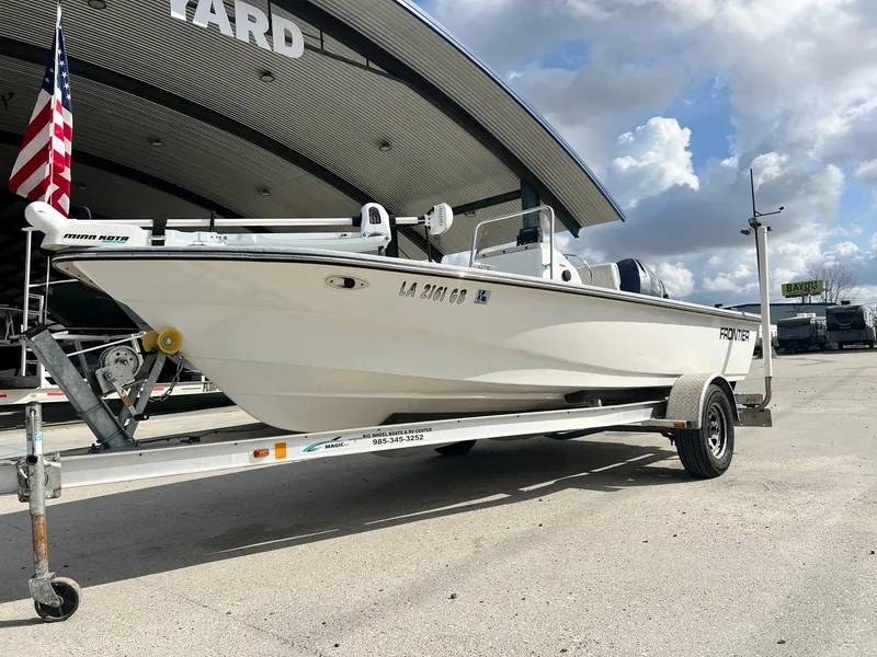 Slide: The Image of 2013 Frontier F-18 boat on trailer, parked outdoors under cloudy sky. - 2