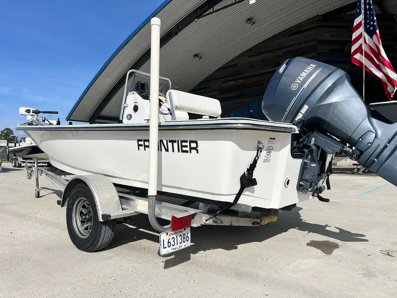 Slide: The Image of 2013 Frontier F-18 boat on trailer with Yamaha motor, parked near a building. - 9