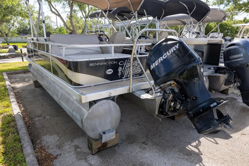Slide: The Image of 2012 Bennington 22 SSL pontoon boat with Mercury outboard motor, parked on a trailer. - 2