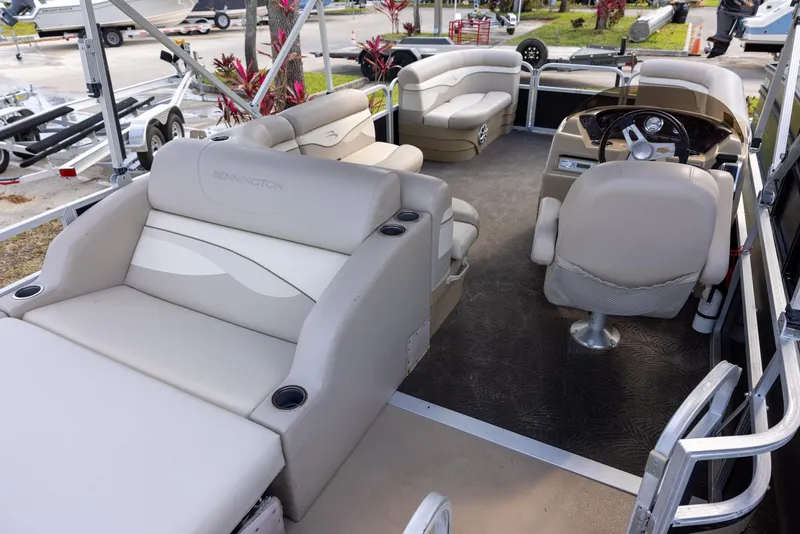Slide: The Image of 2012 Bennington 22 SSL pontoon boat interior with beige seating and steering console. - 4