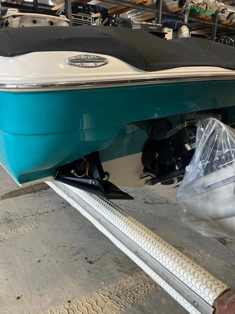 Slide: The Image of 1997 Donzi 27 ZX boat in storage, teal and white hull, visible outdrive. - 8