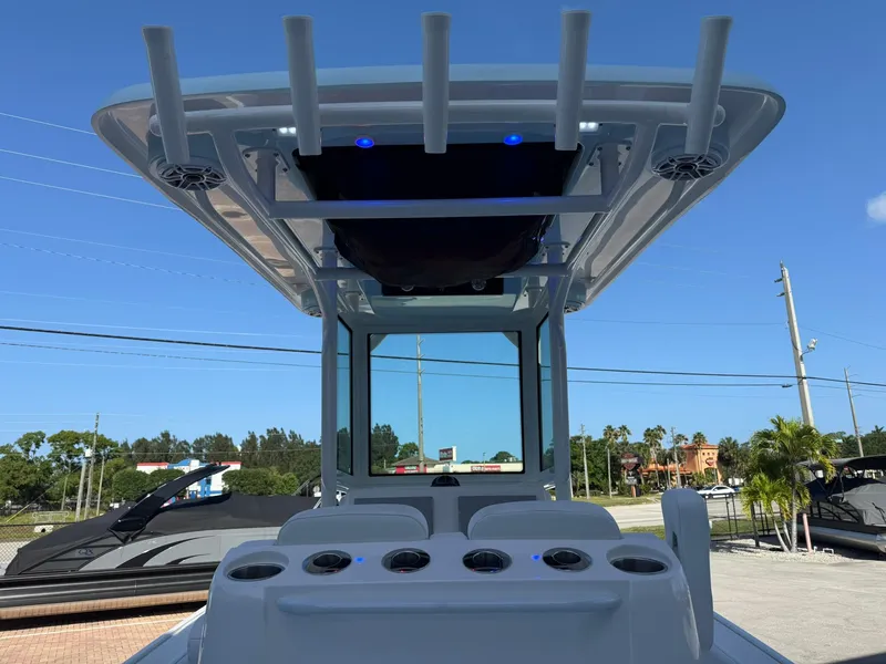 Slide: The Image of 2024 Caymas 26 HB boat with T-top and rod holders, parked outdoors. - 10