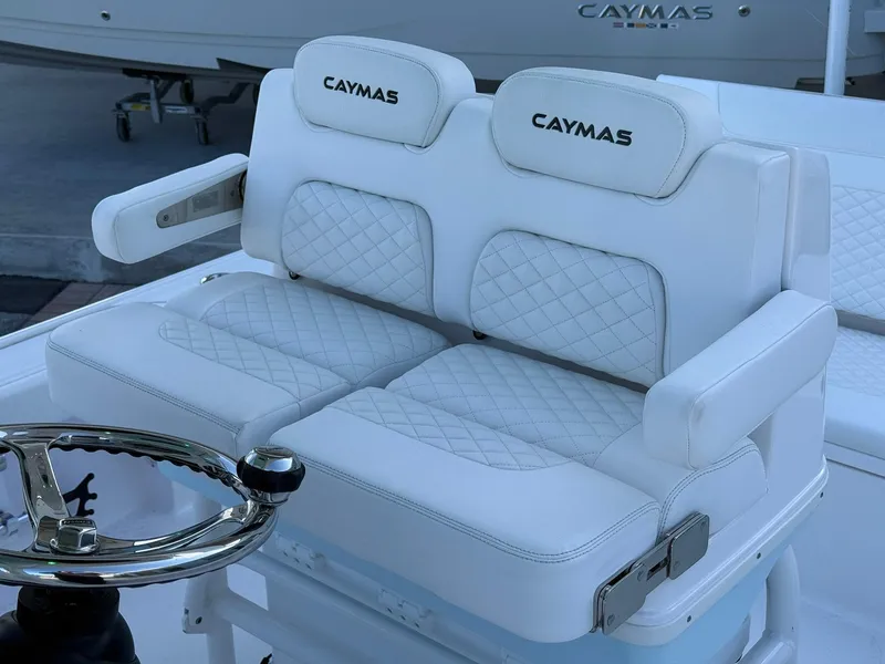 Slide: The Image of 2024 Caymas 26 HB boat with luxurious white cushioned seating and steering wheel. - 16
