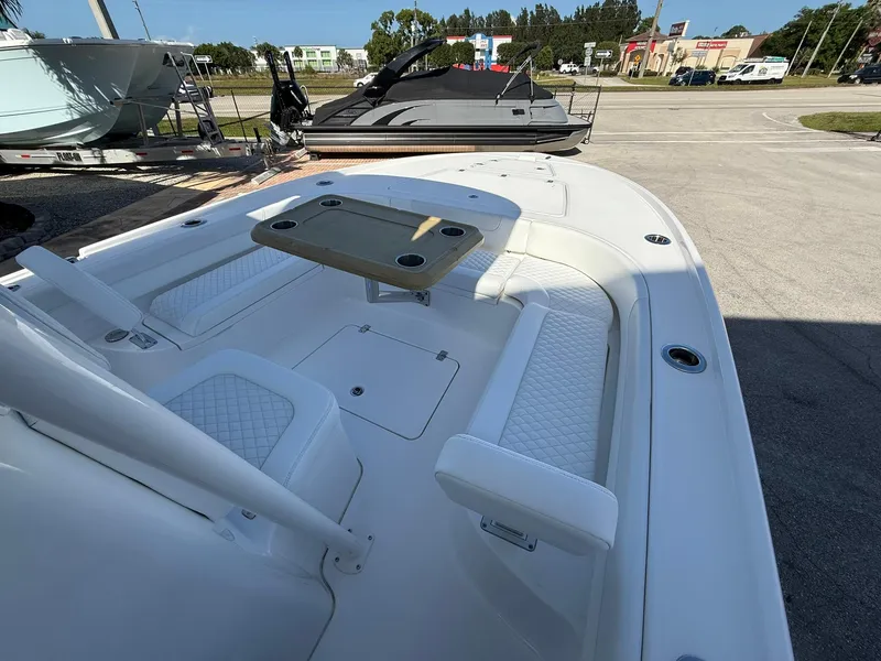 Slide: The Image of 2024 Caymas 26 HB boat interior with seating and table, parked outdoors. - 20