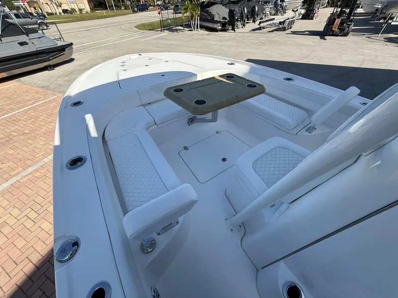 Slide: The Image of 2024 Caymas 26 HB boat interior with seating and table, docked outdoors. - 21