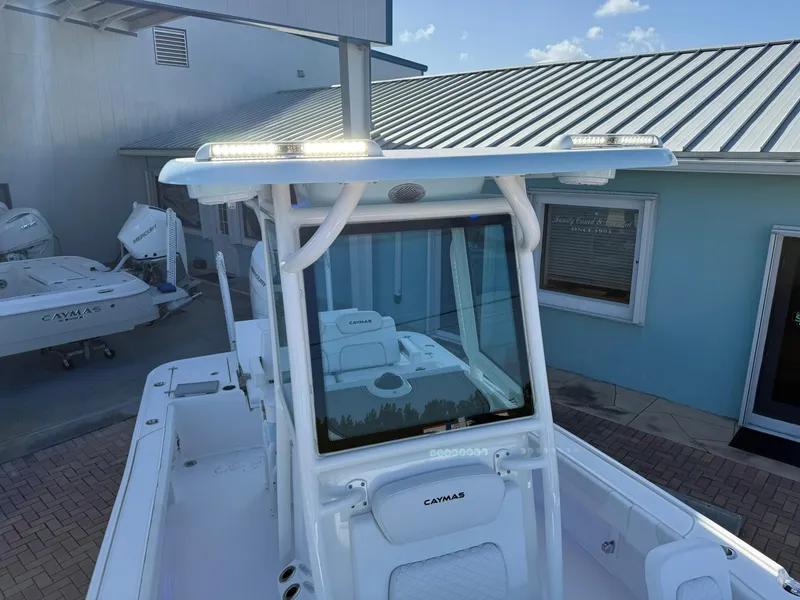 Slide: The Image of 2024 Caymas 26 HB boat with T-top, docked near blue building. - 28