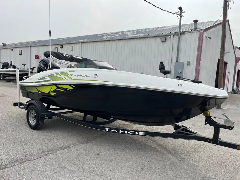 Slide: The Image of 2021 Tahoe T16 boat on trailer, parked outside a warehouse. - 13