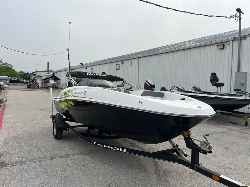 Slide: The Image of 2021 Tahoe T16 boat on trailer, parked outdoors near a warehouse. - 14