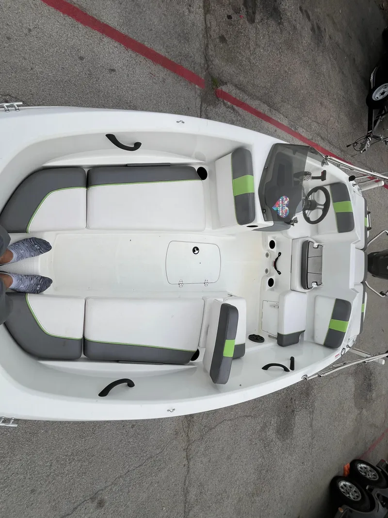 Slide: The Image of 2021 Tahoe T16 boat interior with gray and green seating, steering wheel, and storage compartments. - 15