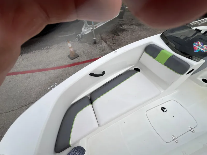 Slide: The Image of 2021 Tahoe T16 boat interior with white and green seating, docked outdoors. - 16