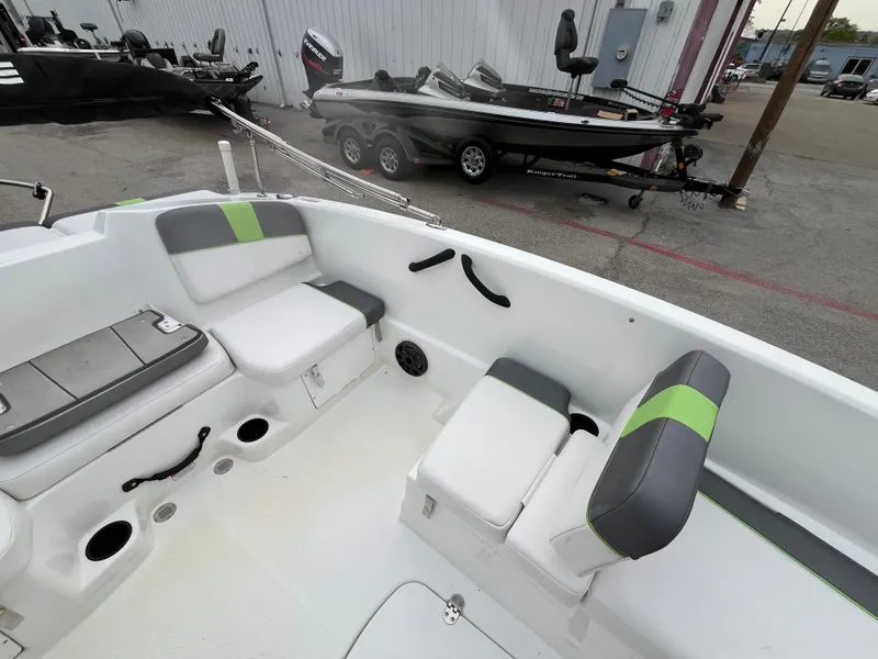 Slide: The Image of 2021 Tahoe T16 boat interior with gray and green seating, docked near trailers. - 22