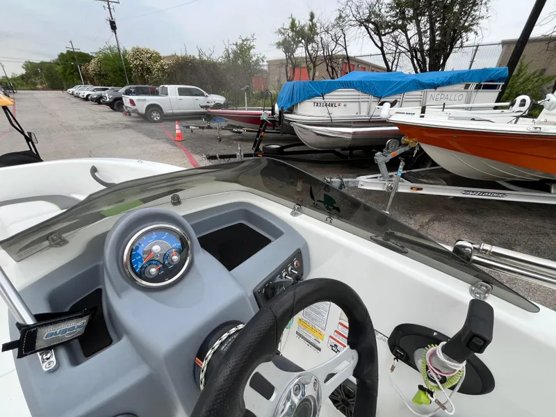 Slide: The Image of Cockpit view of a 2021 Tahoe T16 boat, parked with other boats and vehicles nearby. - 24