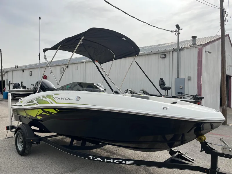 Slide: The Image of 2021 Tahoe T16 boat with canopy on trailer, parked near industrial building. - 29
