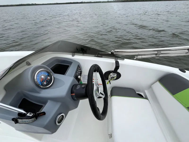Slide: The Image of 2021 Tahoe T16 boat dashboard with steering wheel, gauge, and seating on calm water. - 48