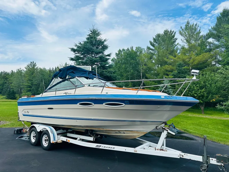 Slide: The Image of 1988 Sea Ray 230 Cuddy boat on trailer, surrounded by lush greenery and blue sky. - 2