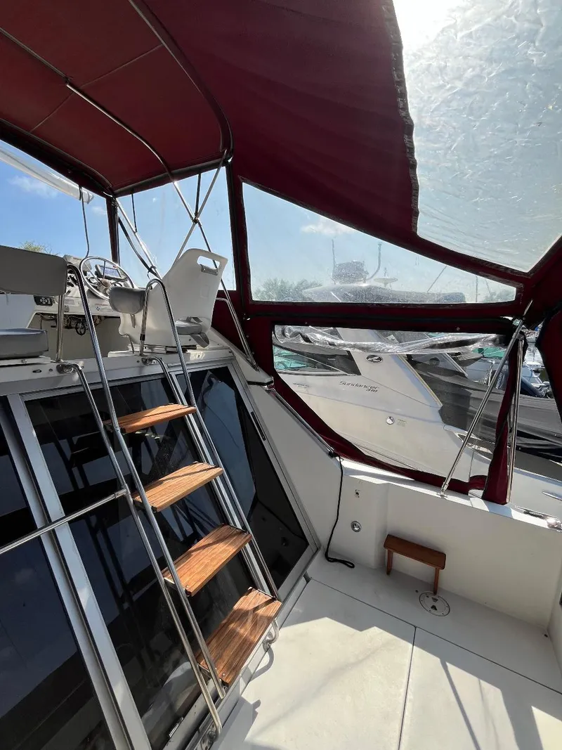 Slide: The Image of 1988 Carver 2767 Santego boat with maroon canopy and wooden steps, docked in sunlight. - 26