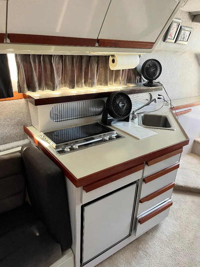 Slide: The Image of 1988 Carver 2767 Santego boat interior with kitchenette, featuring stove, sink, and storage cabinets. - 28