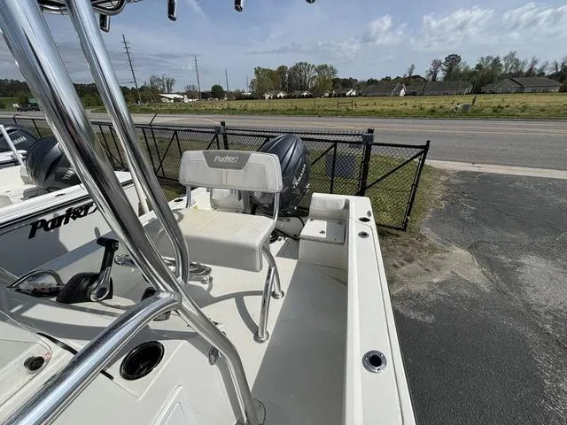 Slide: The Image of 2024 Parker 18 SE boat with seating and motor, parked near a fence. - 5