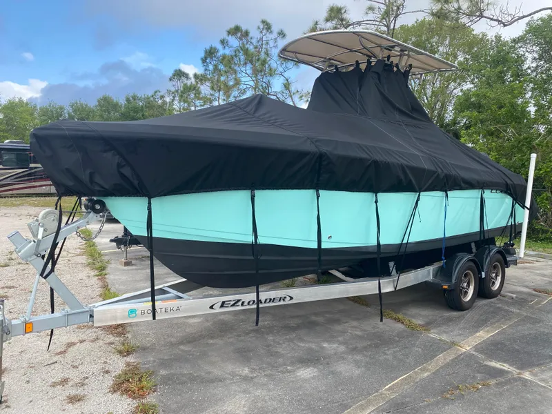 Slide: The Image of 2021 Cobia 237 Center Console boat on trailer, covered with black tarp. - 34