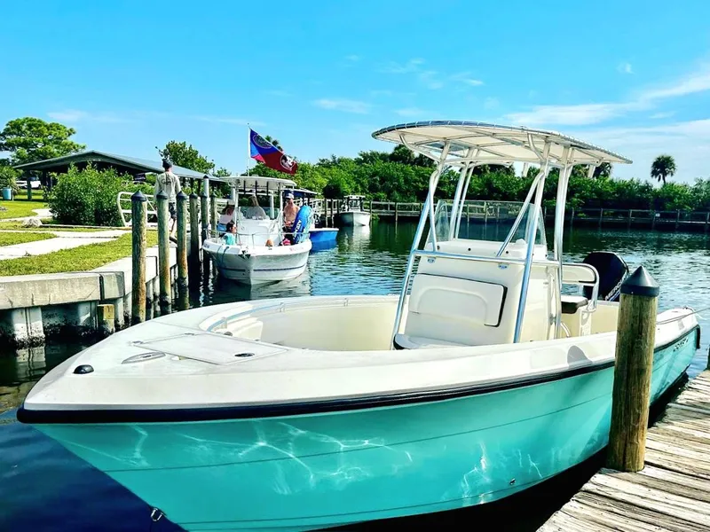 Slide: The Image of 2021 Cobia 237 Center Console boat docked in a sunny marina setting. - 36