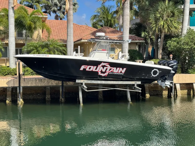 The Image of 2008 Fountain 34 Center Console boat docked by palm trees and waterfront homes. - 0
