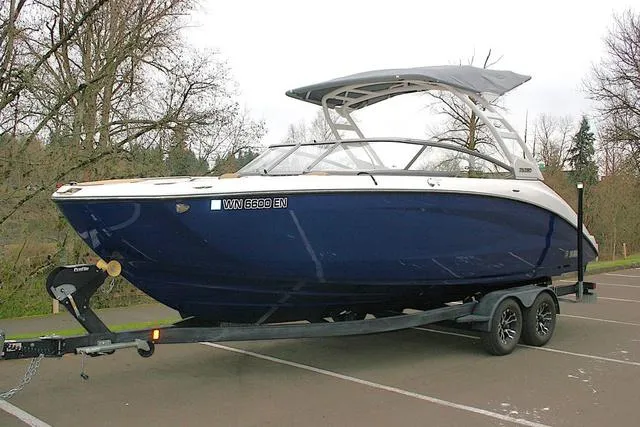Slide: The Image of 2022 Yamaha Boats 252SD on trailer, parked in a lot, with trees in the background. - 1