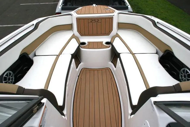 Slide: The Image of 2022 Yamaha Boats 252SD interior with tan and white seating, wood-style flooring. - 10