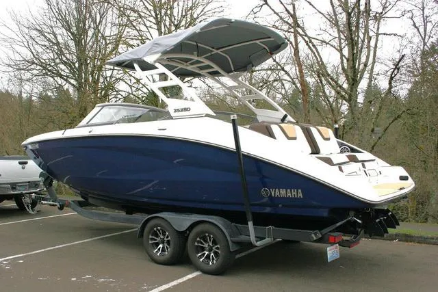 Slide: The Image of 2022 Yamaha Boats 252SD on trailer, parked outdoors, featuring sleek design and blue hull. - 3